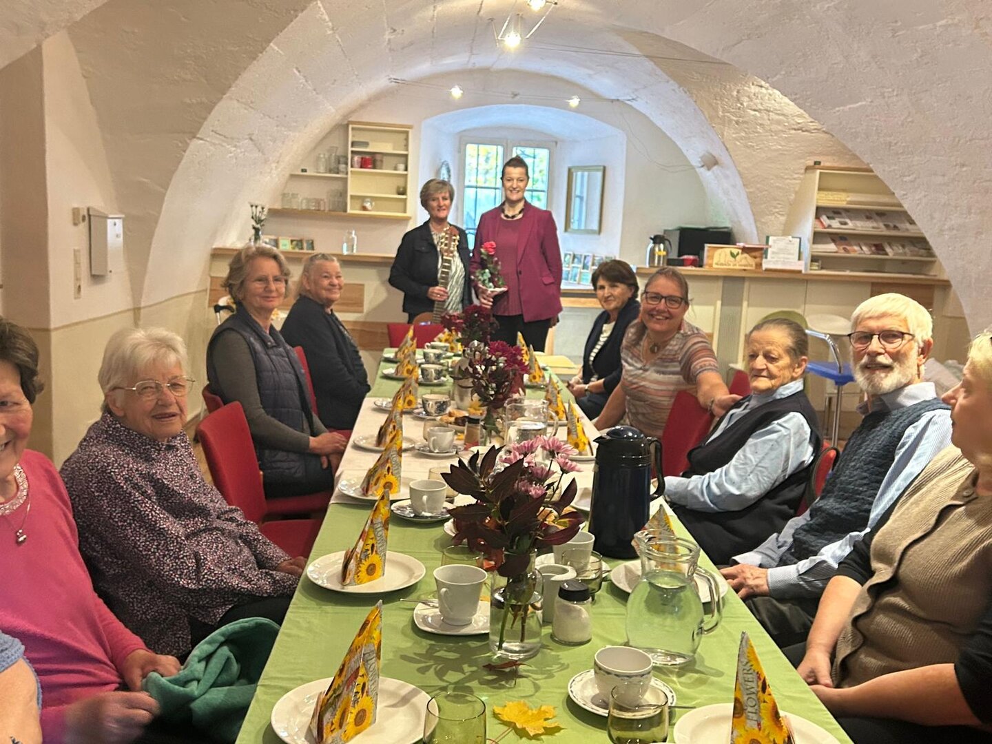 Gruppe von älteren Menschen sitzt an einem Tisch in einem Gewölbekeller.
